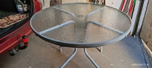 Masă de grădină din sticlă cu schelet metalic și scaun rabatabil.